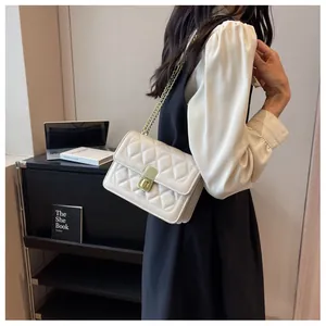 Sac bandoulière beige matelassé avec chaîne dorée, porté pour les trajets quotidiens