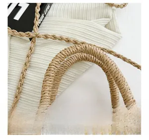 Detail of woven straw bucket bag featuring pearl embellishments and a sturdy handle