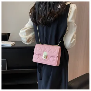 Détail d'un sac bandoulière matelassé rose avec chaîne dorée porté par un mannequin