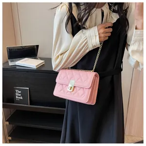 Détail d'un sac bandoulière rose matelassé avec chaîne dorée porté par un mannequin