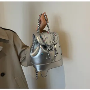 Detail of silver metallic mini backpack with colorful rhinestones and chain strap