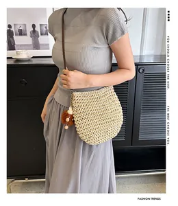 Detail van crème handgeweven crossbodytas met pompon en houten bedeltjes