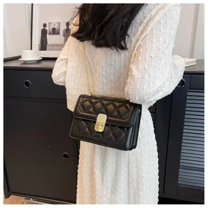 Sac à bandoulière matelassé noir moderne avec chaîne dorée portée par un mannequin