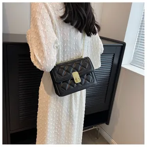 Détail de la texture matelassée noire et de la bandoulière en chaîne dorée du sac