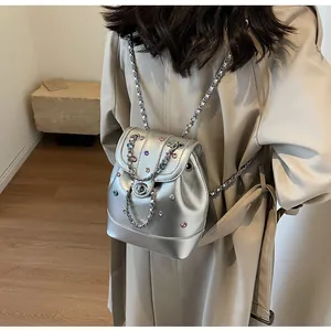 Close-up of silver Y2K mini backpack with colorful gems and metal chain straps