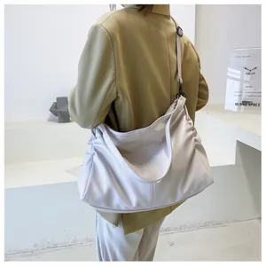 Detalle de bolso hobo de piel sintética crema con correa y pliegues laterales