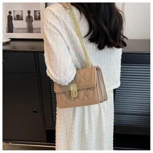 Détail du sac bandoulière matelassé beige avec chaîne dorée et fermoir pivotant en métal