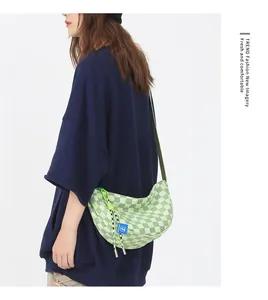 Detail van model met een groene geruite canvas crossbodytas met verstelbare riem