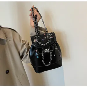Detail of black mini backpack with silver chain strap and colorful rhinestones on a model
