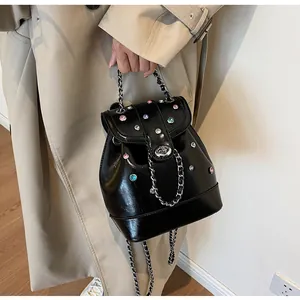 Detail of a shiny black mini backpack with colorful rhinestones and silver chain strap