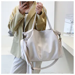 Detalle de bolso tote crema en piel sintética con textura granulada y pliegues suaves