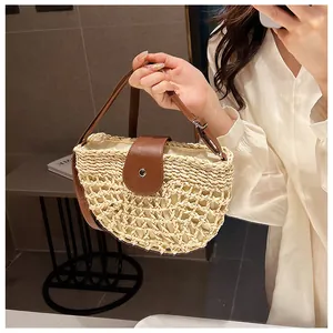 Detail view of straw woven bag showing contrast leather strap and hollow mesh texture