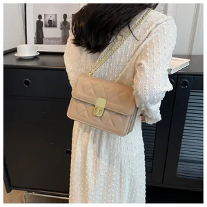 Gros plan du sac beige matelassé avec bandoulière chaîne dorée et fermoir carré