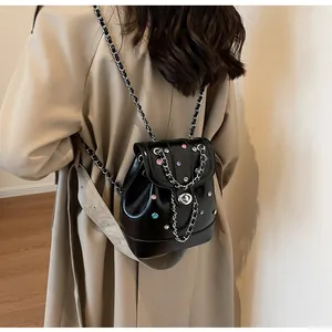 Close-up of a Y2K style black glossy mini backpack with colorful rhinestones and chain strap