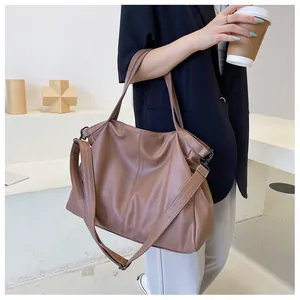 Detalle de bolso tote marrón de cuero PU con correa ajustable sobre chaqueta negra