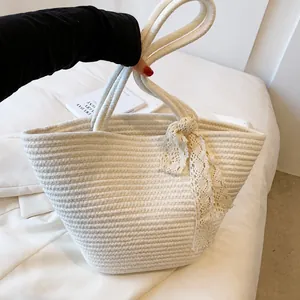 Detail of hand-woven cotton rope beach bag with decorative lace ribbon and cream finish