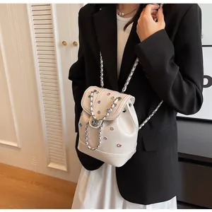 Detail view of a white mini backpack with colorful rhinestones and silver chain strap