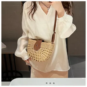 Detail of woven straw crossbody bag with brown leather flap and adjustable metal buckle