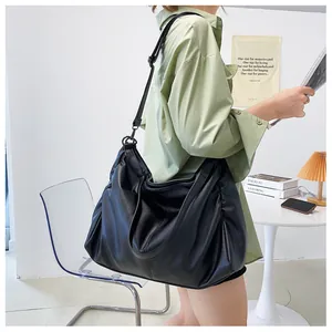 Detalle de un bolso hobo grande de cuero negro suave con textura granulada y correas dobles