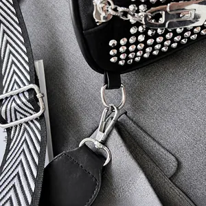 Détail du crochet argenté et du sac clouté avec bandoulière en tissu chevron