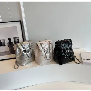 Detailed row of three mini sequined leather backpacks in silver, cream, and black colors