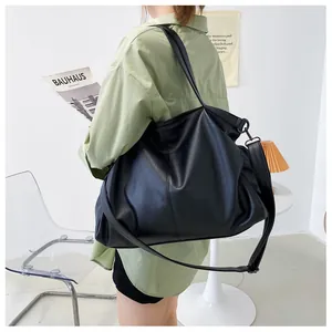 Detalle del bolso tote negro de gran capacidad con textura de grano y correa ajustable