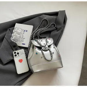 Detail view of silver Y2K mini backpack with colorful rhinestones on a gray blazer