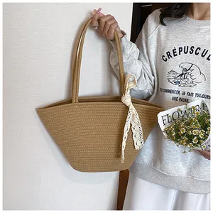 Detail of hand-woven straw tote bag with white lace bow and sturdy woven handles