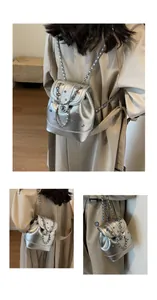 Close-up of silver metallic Y2K backpack with colorful rhinestones and chain straps