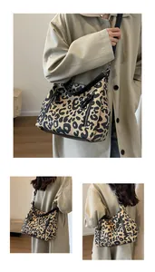 Detail of leopard print tote bag featuring black leather straps and functional side zippers