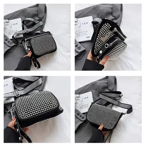Détail d'un sac bandoulière noir à rivets avec une large bandoulière à chevrons stylée