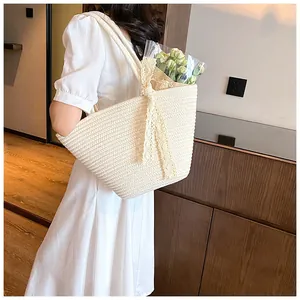 Spacious beige woven tote bag with lace bow detail shown in a lifestyle interior scene