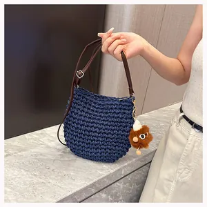 Detail van blauwe geweven schoudertas met lederen riem en bruine pluche dierenhanger