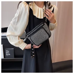 Détail du sac bandoulière punk noir avec clous argentés et large sangle rayée sur modèle
