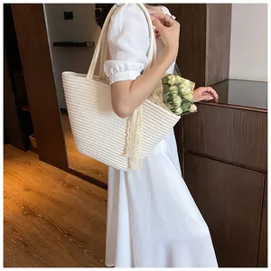 Detailed view of cream woven straw tote bag featuring elegant lace tassel and large capacity