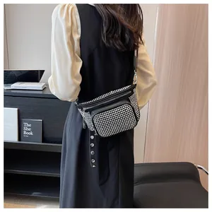 Détail d'un sac bandoulière noir avec rivets argentés et large sangle de style punk