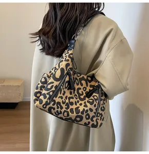 Detail of trendy leopard print tote bag featuring black leather straps and zip pocket