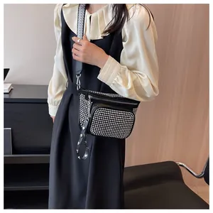 Détail d'un sac bandoulière noir avec rivets argentés et large sangle rayée