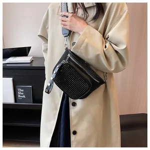 Détail d'un sac bandoulière noir en strass avec une large sangle rayée sur un mannequin