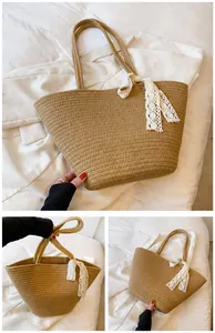 Detail of khaki straw tote bag with elegant white lace bow and durable shoulder straps