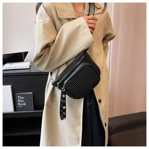 Détail macro du sac ceinture noir chic avec clous, bandoulière large et strass brillants