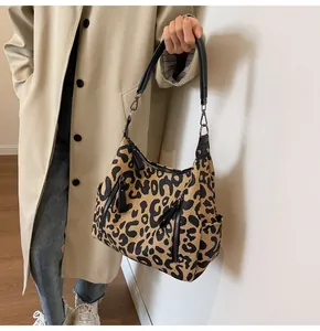 Detail of leopard print tote bag featuring dual vertical zippers and wide black strap