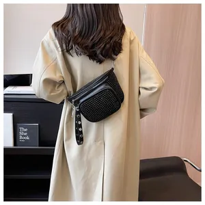 Détail du sac ceinture noir à strass avec zips métalliques sur un trench-coat