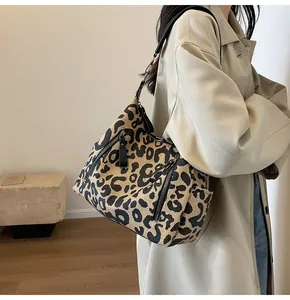 Detail view of large leopard print tote bag featuring multiple zip pockets and black strap
