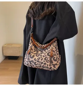 Detail of leopard print tote bag with metal zippers and dark brown leather straps