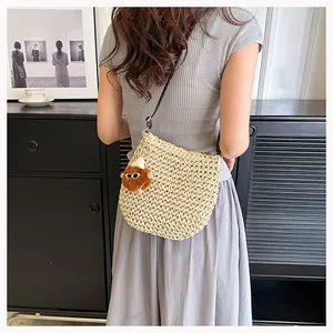 Detail van handgeweven strooien tas met beige textuur, pluche hanger en leren riem