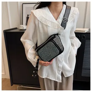 Détail du sac à bandoulière noir avec strass et large sangle aux motifs géométriques