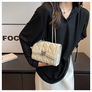 Détail du sac matelassé crème avec boucle en cœur argentée et petits clous en métal