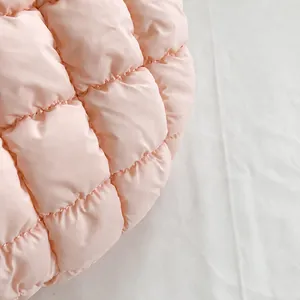 Detailopname van de roze gewatteerde stoftextuur met fijne stiksels op een puffy cloud bag
