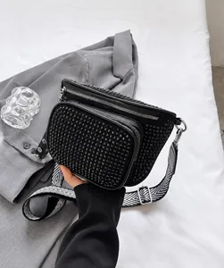 Détail d'un sac banane noir orné de strass avec une bandoulière large à chevrons